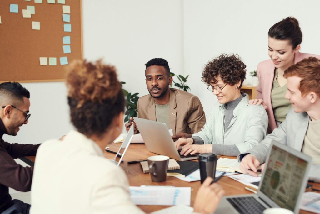 Office workers gathered around the table against a gray background.