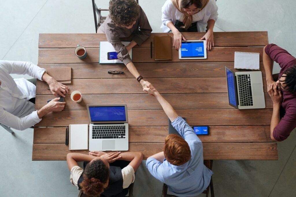 Coworkers shake hands around a table