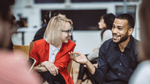 A young male chats with a smiling female in a networking setting