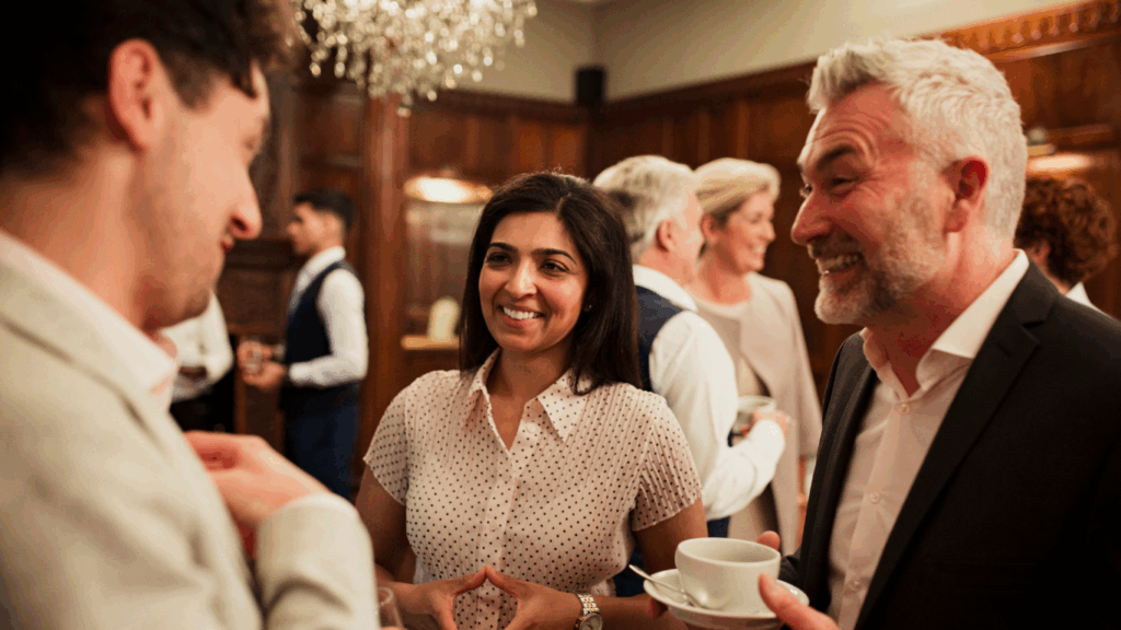 An older male executive interacts with two others in a networking setting